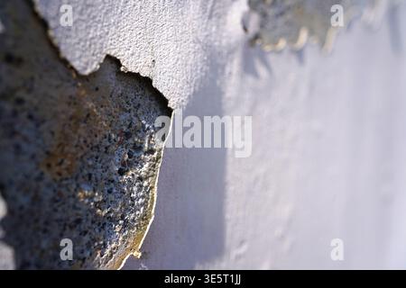 Weathered concrete wall with cracked white paint peeling off, macro stone texture Stock Photo