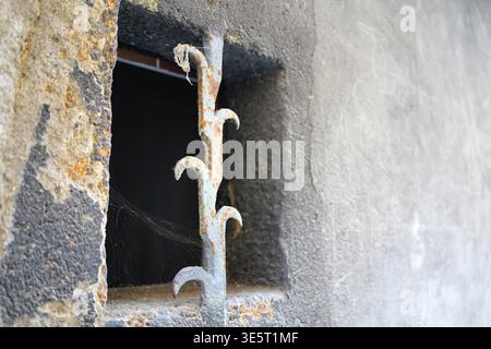 Ancient wrought iron window grate with sharp thorns in a medieval stone wall Stock Photo