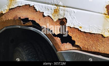 Corroding car body showing severe rust and peeling white paint on a wheel arch in Moscow Stock Photo