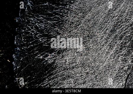 Cracked black glass texture, shattered dark surface background with spider web fracture pattern and broken glass detail Stock Photo