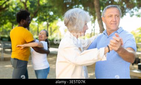Elderly woman enjoying dance with partner in garden Stock Photo