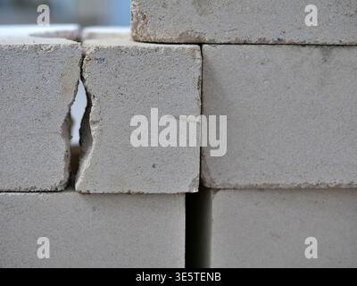 stacked light-colored masonry blocks with a focus on a broken edge and structural  cracks, industrial building materials on a construction site, raw t Stock Photo