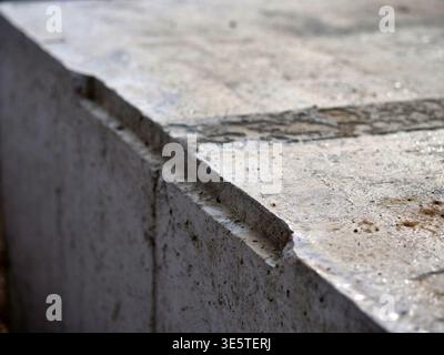 macro photo of concrete edge with rough texture, close up of grey cement wall corner at  construction site, industrial background showing weathered co Stock Photo