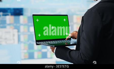 Business specialist using green screen laptop to review performance dashboards metrics. Management executive evaluating annual report data using chroma key notebook, camera B Stock Photo