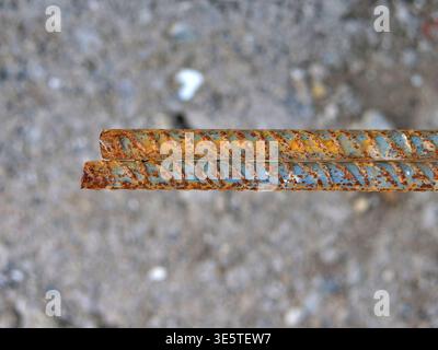 top down macro photo of two rusty ribbed steel rebar ends, close up of rusted reinforcement  bars for concrete on grey ground, industrial metal textur Stock Photo