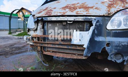 Abandoned rusty van front bumper with damaged radiator and peeling paint outdoors Stock Photo