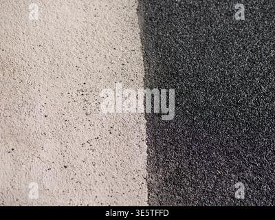 Close up of two different asphalt textures. Light grey versus dark black tarmac surface. Vertical divide between old and new pavement. Grainy road sur Stock Photo