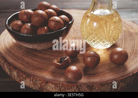 Bottle of macadamia oil, on a wooden board, with macadamia nuts, wooden background, selective focus, no people Stock Photo