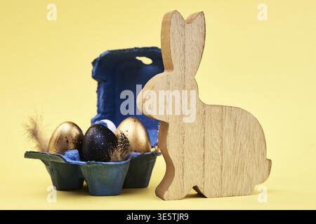 Wooden rabbit and colored eggs on yellow background, Happy Easter card Stock Photo