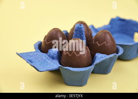 Chocolate eggs in blue box on yellow background with cope space, Happy Easter Stock Photo