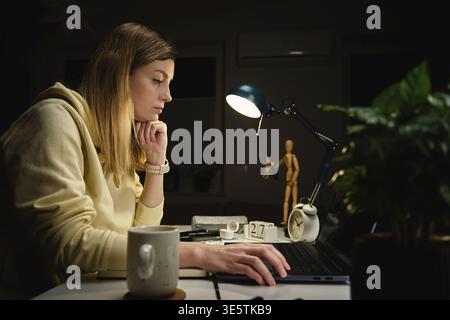 Tired woman works from home use laptop at night, overwork burnout, freelancer works remote at home workplace Stock Photo