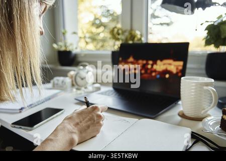 Freelancer working from home. Creative designer drawing illustration at notebook. Remote working workplace with laptop on the table Stock Photo