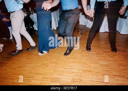 Casual Motion Captured Of Guests Dancing On Polished Wooden Floor During Happy Wedding Celebration Stock Photo