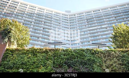 Green wall growing in front of a curved modern building with solar panels Stock Photo