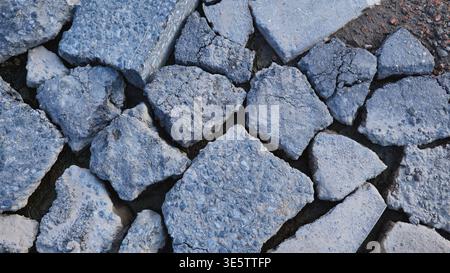 Broken asphalt pieces creating abstract texture, road destruction and demolition debris Stock Photo