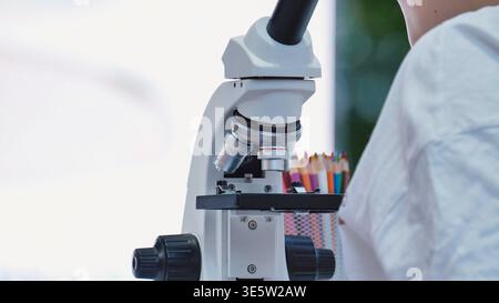 Student learning science using microscope in a school laboratory for education and research Stock Photo