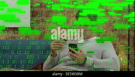 Sitting man wearing shirt tapping smartphone with stylus at home on blue sofa, green binary overlay Stock Photo