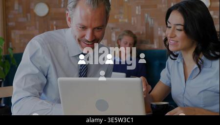 Leaning man in tie and woman in blouse pointing at silver laptop in cafe with avatars Stock Photo