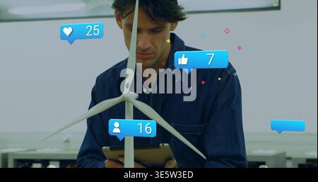 Inspecting man in denim shirt with tablet in lab, checking wind turbine model with social icons Stock Photo
