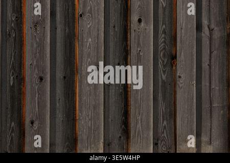 Close-up of dark vertical wooden planks with warm brown seams, photographed full frame as a rustic abstract wood texture background. Stock Photo