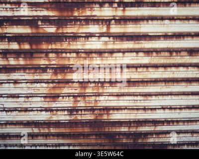 A weathered and rusty metal shutter door showing deep corrosion and industrial textures in an urban environment Stock Photo