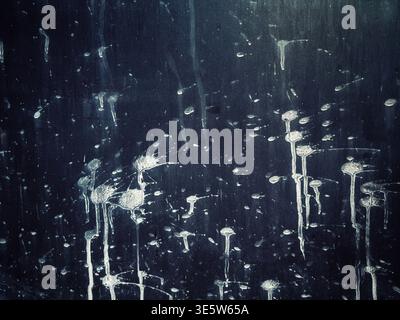 Abstract texture of splattered white paint or water droplets on a dark black weathered surface Stock Photo