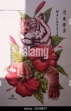 Tiger rests beside vibrant red hibiscus flowers. Lush green leaves frame the bold floral design. Artwork features realistic animal and plant details. Stock Photo