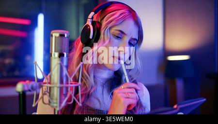 Thinking, woman and musician with notebook in studio for songwriting, writing lyrics and recording audio. Person, reflection and headphones with mic Stock Photo
