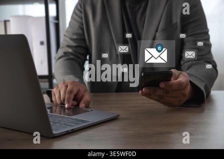 Businessman using smartphone and laptop with email security protection interface, message icons and cybersecurity shield. data protection, phishing pr Stock Photo