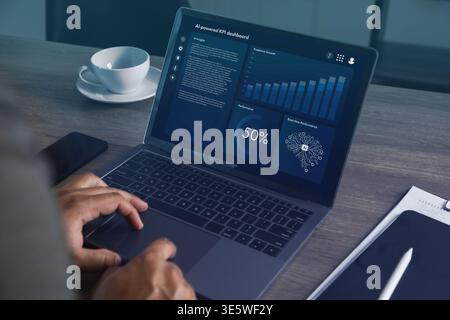 Hands operating laptop with AI powered analytics dashboard featuring charts, graphs, and performance indicators in office setting, representing data m Stock Photo