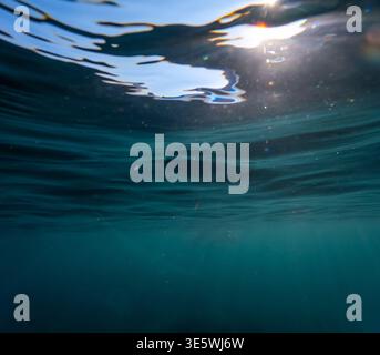 Underwater ocean sunlight filters through the blue water surface from below to create a tranquil and serene aquatic atmosphere Stock Photo
