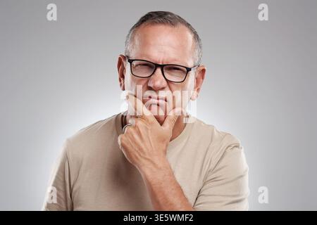 Confused, portrait and unsure with man in studio for puzzled or uncertain facial expression. Disagree, doubt and skeptical with mature person on white Stock Photo
