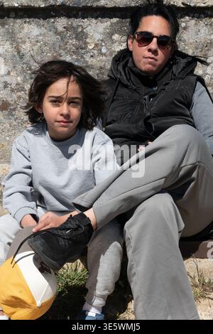 Mother and son casually sitting outdoors, enjoying time together on a sunny day Stock Photo