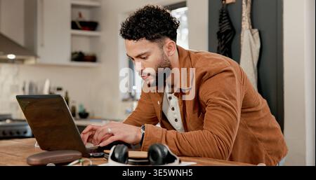Laptop, typing and man in kitchen for freelance, review article or proposal with email in home. Person, remote work and journalist on computer for Stock Photo
