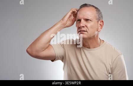 Confused, scratching head and thinking with man in studio for doubt, question or uncertainty. Puzzled, solution and vision with mature person on white Stock Photo