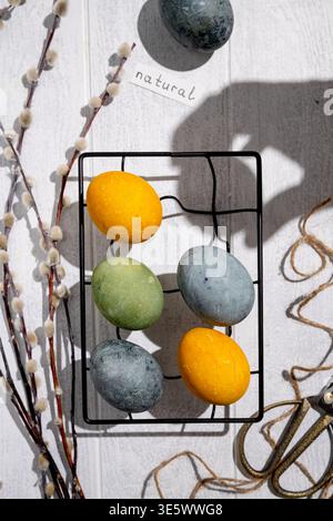 Easter eggs drying on a cooling rack after being naturally dyed with hibiscus and turmeric, creating a beautiful display of yellow and green hues, rea Stock Photo