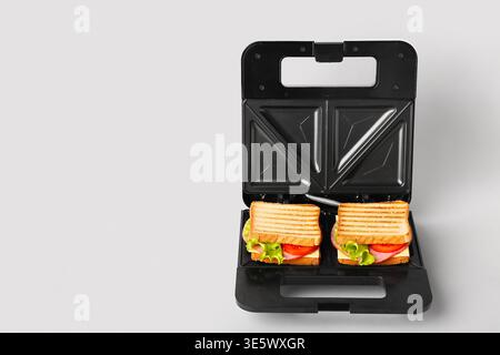 Modern sandwich maker with delicious grilled sandwiches on white background Stock Photo