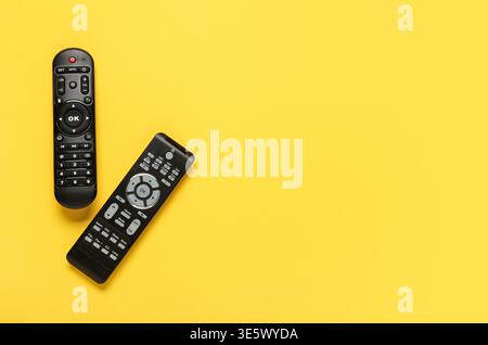 Different modern TV remote controls on yellow background Stock Photo