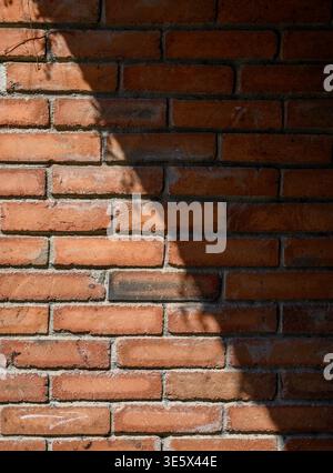 High-resolution photo of an old brick wall illuminated by sunlight, casting diagonal shadows across its textured surface. Ideal for backgrounds, rusti Stock Photo