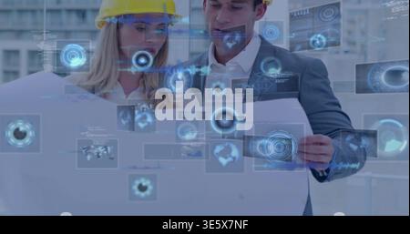 Studying engineer in yellow helmet and manager in suit examining plan in office with AR overlays Stock Photo