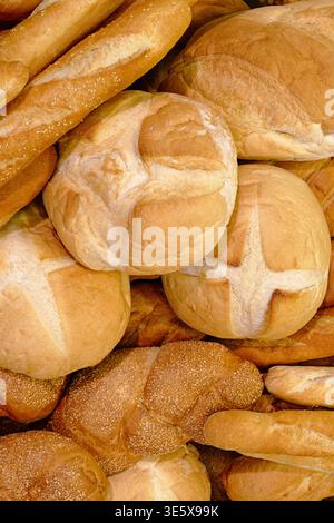 Various types of white wheat bread - loaves, baguettes, buns, rolls. Close-up shot, abstract bakery and food industry background Stock Photo