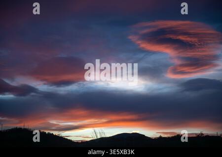 Colorful sunset sky with dramatic clouds over mountain horizon Stock Photo