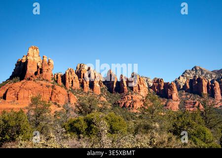 Red rock spires and cliffs rising above lush desert vegetation Stock Photo