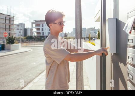 Young person pressing intercom button of residential complex Stock Photo