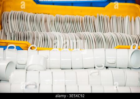 Stacked white ceramic cups and plates in plastic crates Stock Photo