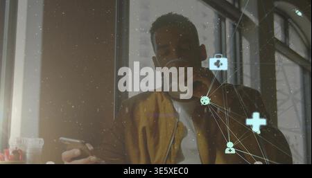 Holding phone, man wearing brown jacket white tee sipping paper cup by window with AR graphics Stock Photo