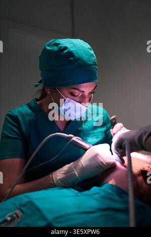 Dentist performing dental procedure on patient in a clinical setting with protective mask and gloves Stock Photo
