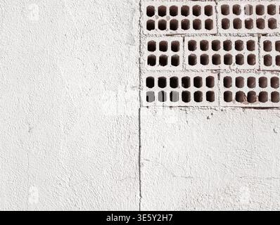 White Painted Wall with Exposed Perforated Bricks Stock Photo