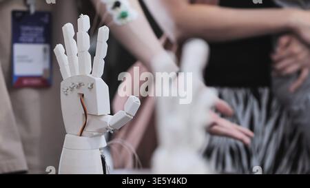 Close up of a white bionic hand prototype with a person and sensors blurred in the background Stock Photo