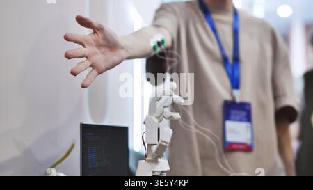 Man controlling a robotic hand with EMG sensors on his arm in a tech lab Stock Photo